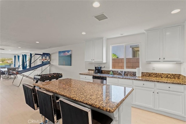 kitchen featuring dark stone countertops, dishwasher, a center island, and white cabinets