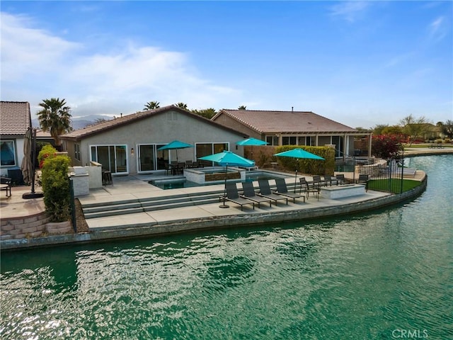 back of property with a patio and a water view