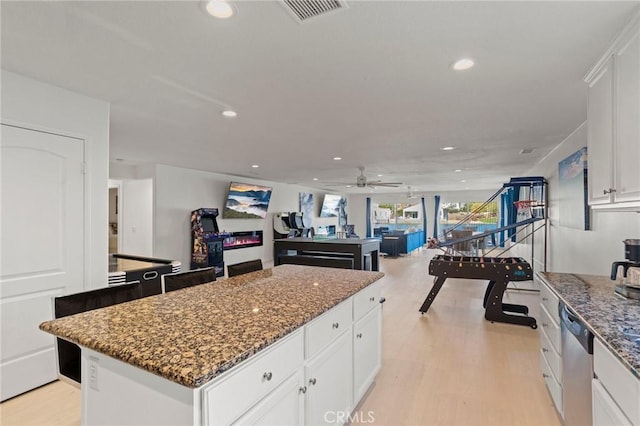 kitchen featuring white cabinetry, dishwasher, a kitchen island, and dark stone countertops