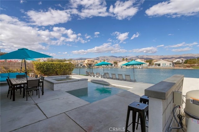 view of pool featuring a water and mountain view, a patio, and an in ground hot tub