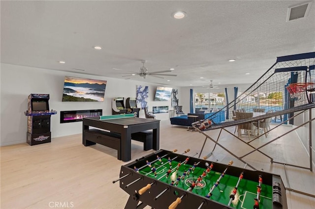 game room featuring hardwood / wood-style flooring, a textured ceiling, and ceiling fan