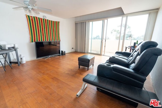 living room with ceiling fan, hardwood / wood-style floors, and a wall of windows