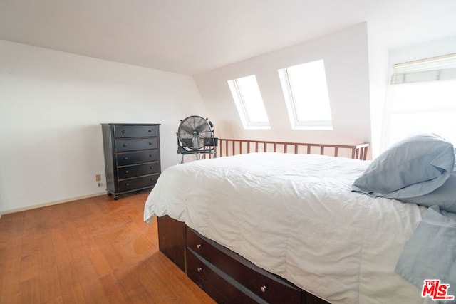 bedroom with a skylight and light hardwood / wood-style flooring