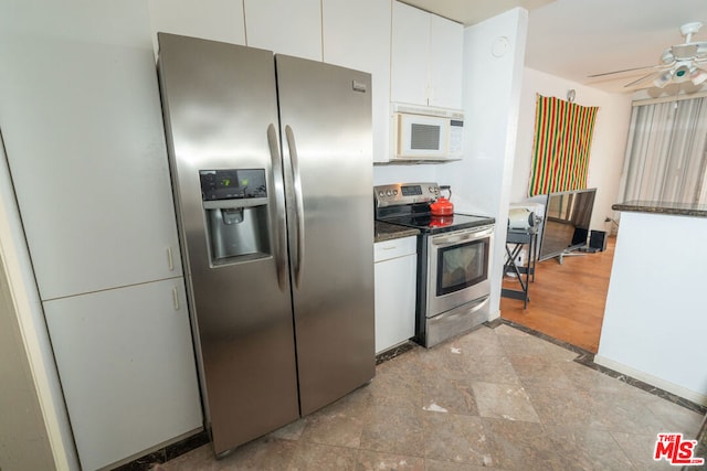 kitchen featuring appliances with stainless steel finishes, white cabinets, ceiling fan, and dark stone counters