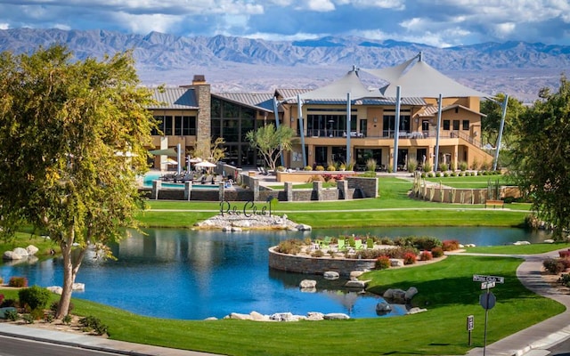 view of property's community with a water and mountain view and a lawn