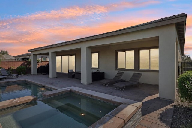 back house at dusk featuring a pool with hot tub, an outdoor living space, and a patio