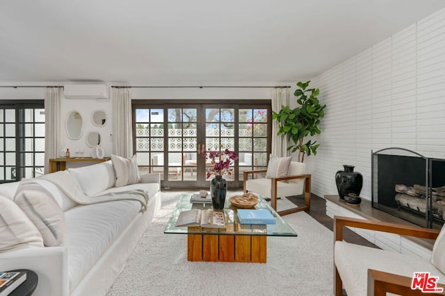 living room with a fireplace, an AC wall unit, and french doors