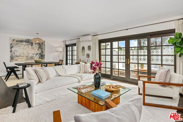 living room featuring light hardwood / wood-style floors, french doors, and a wall mounted AC