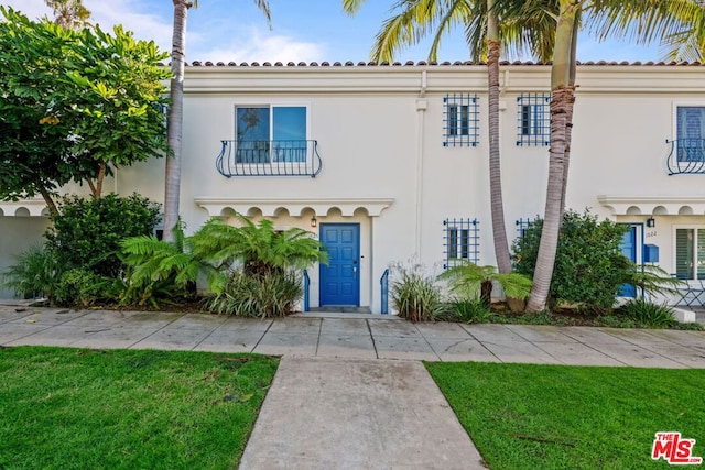 mediterranean / spanish-style house with a balcony and a front lawn