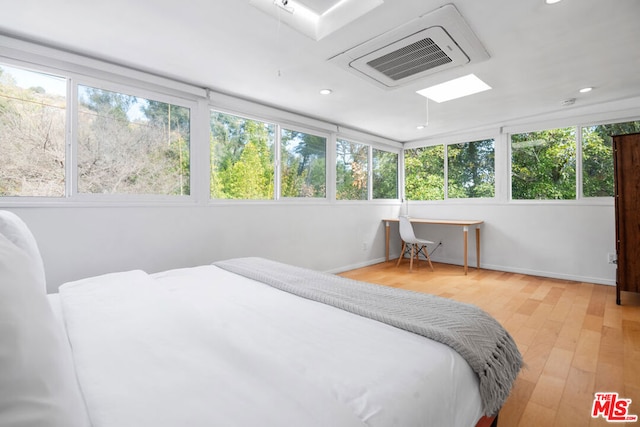 bedroom featuring a skylight and light hardwood / wood-style flooring