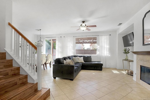 tiled living room with ceiling fan and a fireplace