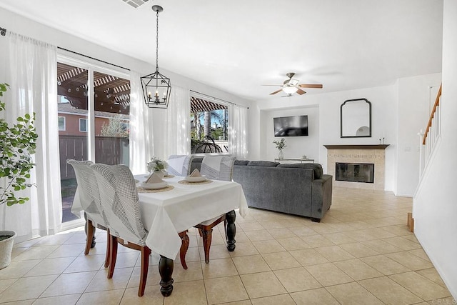 dining space with light tile patterned flooring and ceiling fan with notable chandelier