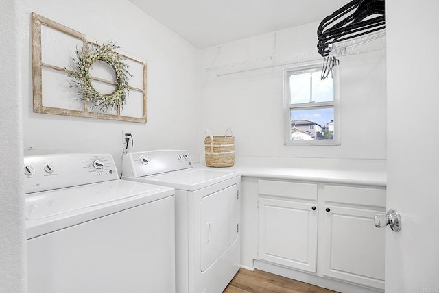 washroom featuring cabinets, washer and clothes dryer, and light hardwood / wood-style flooring