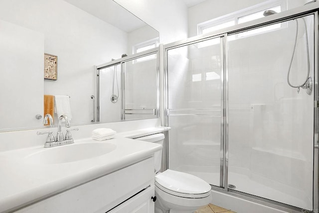 bathroom featuring tile patterned flooring, vanity, a shower with shower door, and toilet