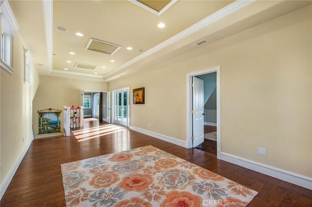 unfurnished room featuring attic access, a raised ceiling, visible vents, and dark wood finished floors