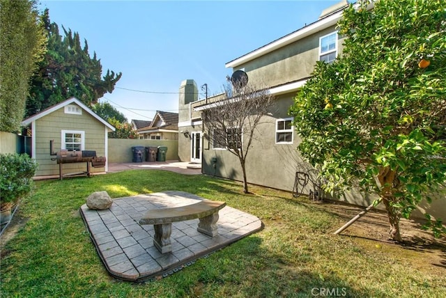 view of yard featuring an outdoor structure, fence, and a patio