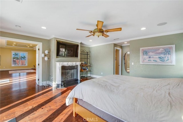 bedroom with baseboards, a high end fireplace, ornamental molding, wood finished floors, and recessed lighting