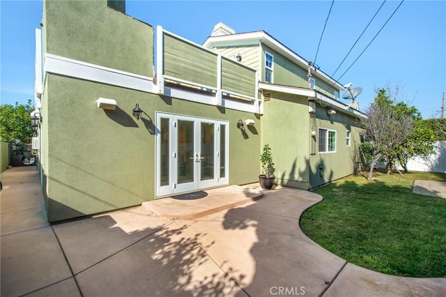 back of property featuring french doors, fence, a yard, a patio area, and stucco siding