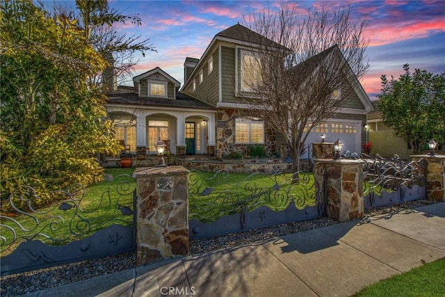 view of front of home featuring a garage, stone siding, a lawn, and a fenced front yard