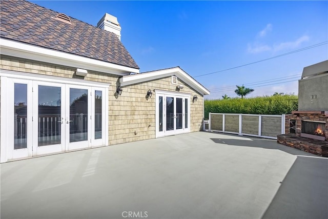 view of patio featuring french doors and a lit fireplace