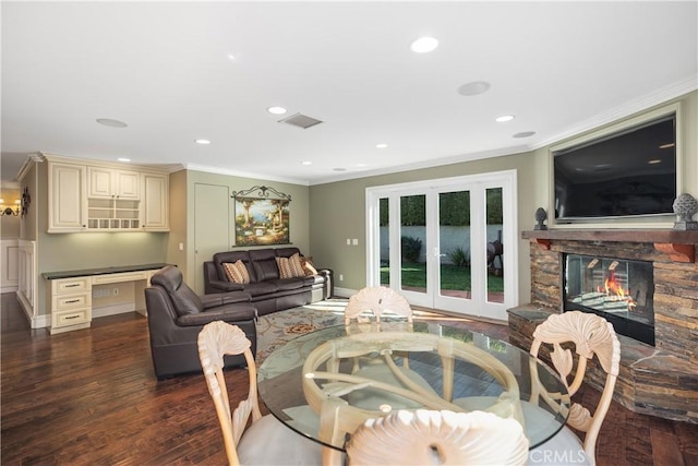 dining area featuring dark wood-style floors, a fireplace, crown molding, and visible vents