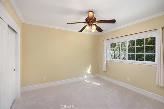 unfurnished bedroom with light carpet, baseboards, ceiling fan, crown molding, and a closet