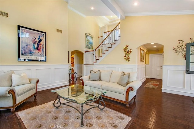 living area featuring ornamental molding, arched walkways, dark wood-style flooring, and stairs