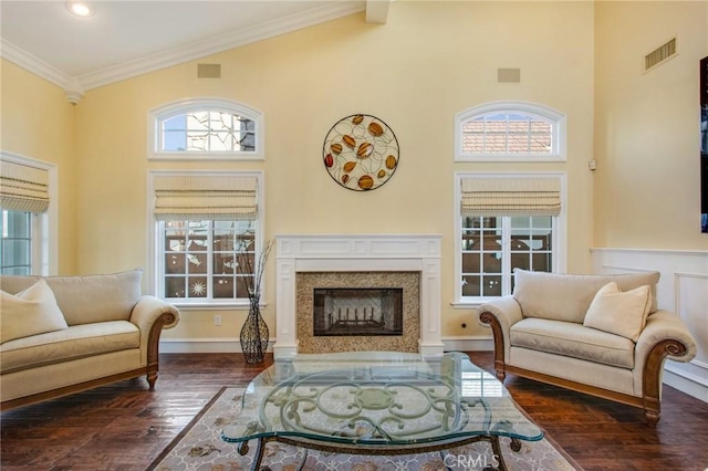 living area featuring a fireplace, visible vents, dark wood finished floors, and ornamental molding