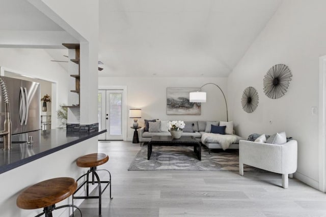 living room featuring french doors, vaulted ceiling, and light hardwood / wood-style flooring