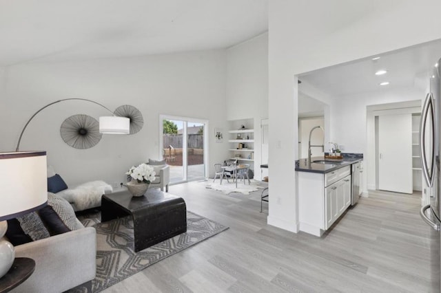 living room with sink, high vaulted ceiling, and light wood-type flooring