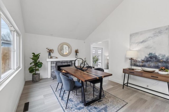 dining area with high vaulted ceiling and light hardwood / wood-style floors