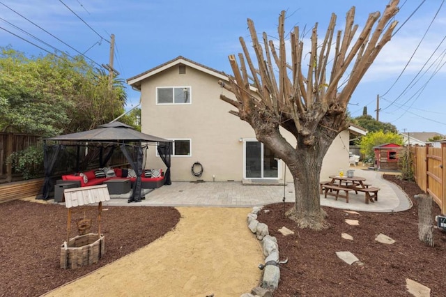 rear view of property featuring a gazebo, a patio area, and an outdoor living space with a fire pit