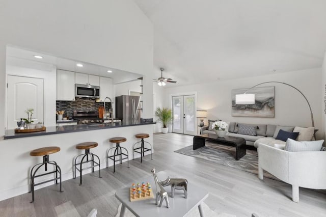 kitchen featuring appliances with stainless steel finishes, white cabinetry, a kitchen bar, french doors, and kitchen peninsula