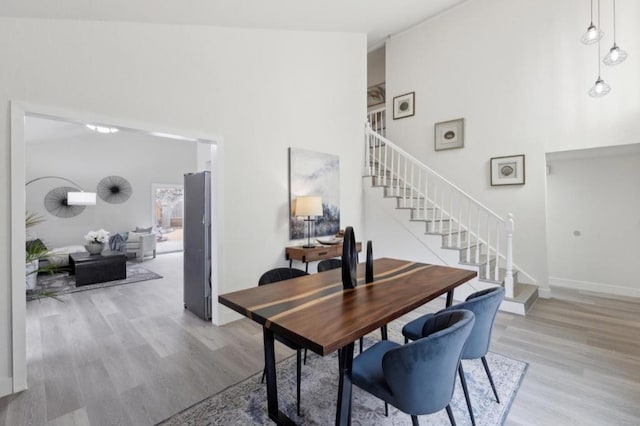 dining room with light hardwood / wood-style flooring and a high ceiling