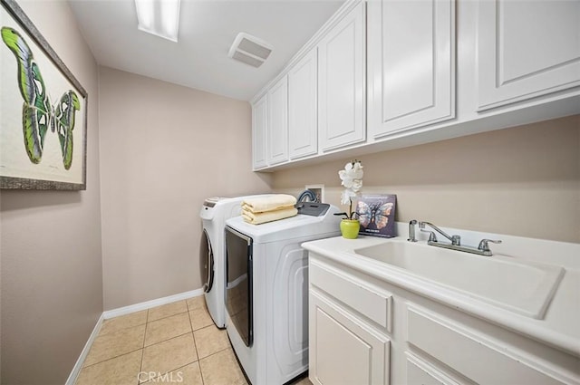 clothes washing area with sink, light tile patterned floors, cabinets, and washer and dryer