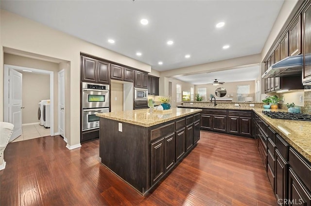 kitchen featuring separate washer and dryer, dark brown cabinets, stainless steel appliances, and a kitchen island