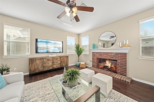 living room featuring ceiling fan, plenty of natural light, dark hardwood / wood-style floors, and a fireplace