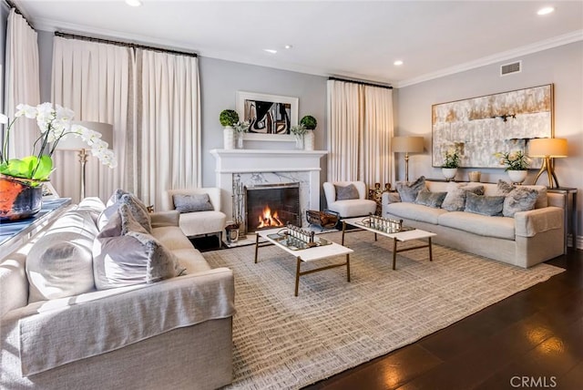 living room featuring wood-type flooring, a high end fireplace, and crown molding