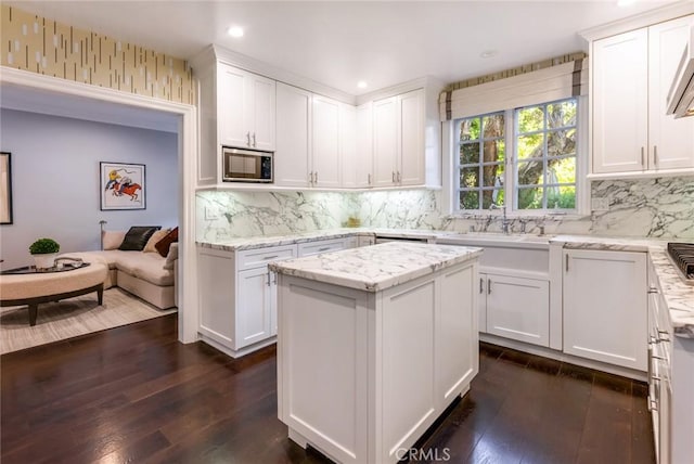 kitchen with a center island, stainless steel microwave, and white cabinets