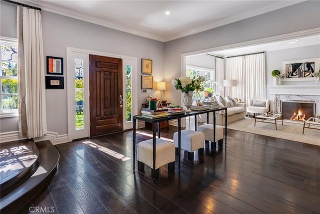 entryway with crown molding, dark wood-type flooring, and a high end fireplace