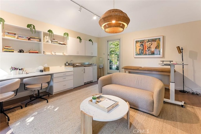 office area with light hardwood / wood-style floors and rail lighting