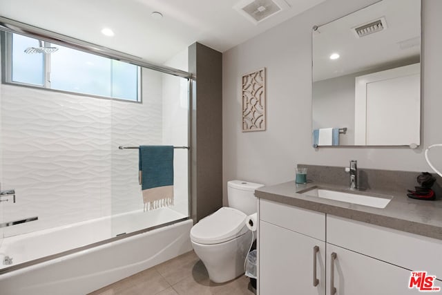 full bathroom featuring vanity, combined bath / shower with glass door, tile patterned floors, and toilet