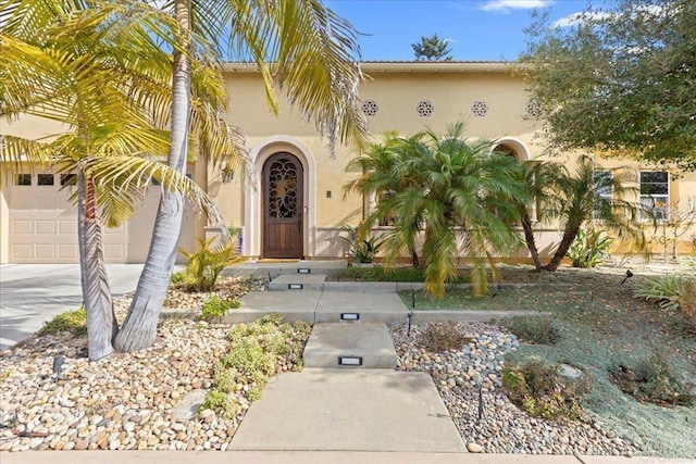 view of exterior entry with stucco siding and concrete driveway