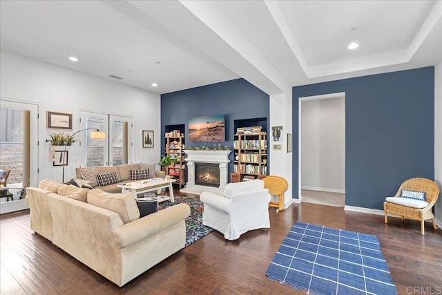 living room featuring recessed lighting, baseboards, a lit fireplace, and wood finished floors