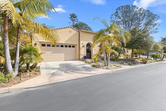 mediterranean / spanish house with a garage, driveway, and stucco siding