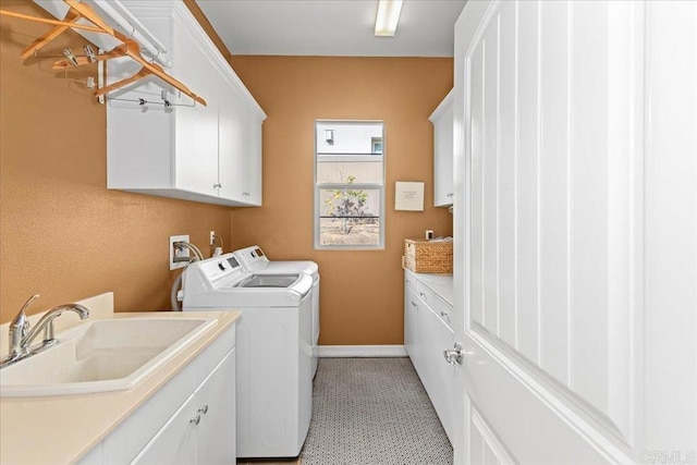 washroom featuring a sink, baseboards, cabinet space, and washer and dryer