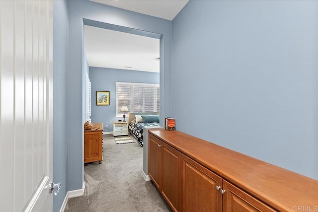 corridor featuring light colored carpet and baseboards