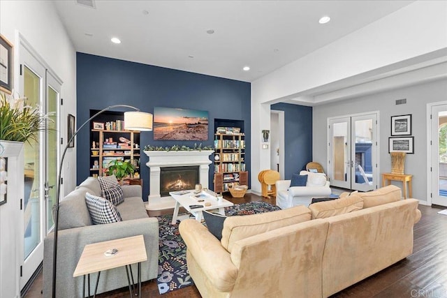 living room with wood finished floors, baseboards, recessed lighting, a lit fireplace, and french doors