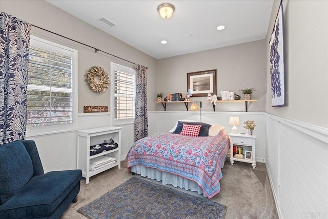 carpeted bedroom with recessed lighting, a wainscoted wall, and visible vents