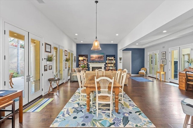 dining area featuring baseboards, dark wood finished floors, a fireplace, recessed lighting, and french doors